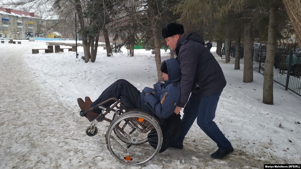 Орынбай Охасов помогает Эрику Жумабаеву доехать до места пикета.