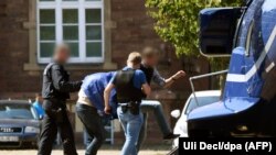 Suspected Islamist militant Magomed-Ali C. (second left, under the blanket) is escorted by German police officers to a helicopter after an arrest hearing at the Federal Court of Justice in Karlsruhe in August last year.