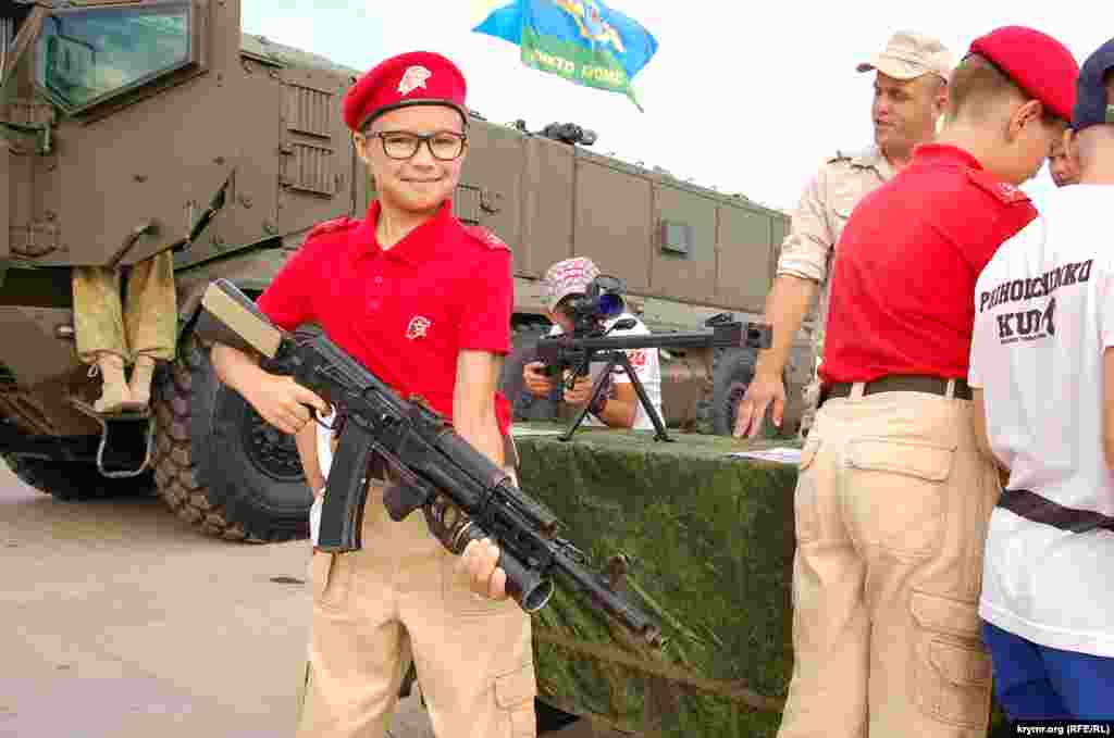 Мальчик в очках с автоматом на выставке стрелковых вооружений