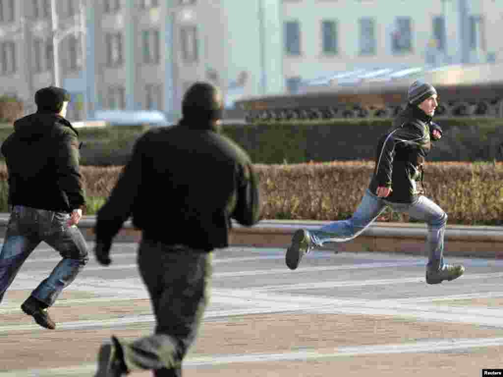 Polițişti din Belarus &icirc;n civil fug după un protestatar &icirc;n Piața Independenței din Minsk. La Minsk pe 7 Noiembrie a fost marcată ziua revoluției bolşevice din1917. (Foto: Vasii Fedosenko pentru Reuter)