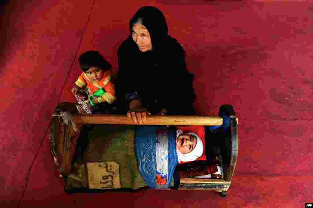 An Afghan woman rocks the cradle of her child at their house on the outskirts of Herat. (AFP/Aref Karimi)