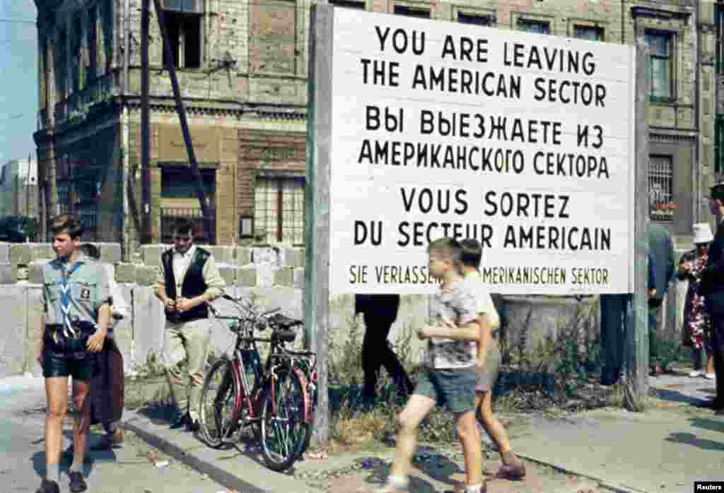 West Berliners walk in front of the Berlin Wall at the American sector&#39;s&nbsp;&quot;Checkpoint Charlie&quot; in Berlin, July, 1963. 