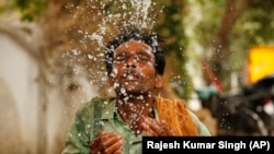 Indijski radnik prska vodom lice da se rashladi u vrelo ljetno popodne u Prayagraju, Uttar Pradesh, Indija, fotoarhiv