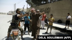 A member of the Syrian Democratic Forces (SDF) indicates a safe street to civilians fleeing the zones controlled by the Islamic State (IS) group on August 7, 2016 in the northern Syrian town of Manbij, a day after SDF retook it from IS.