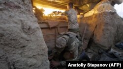 A Ukrainian soldier fires a large-caliber machine gun while another prepares cartridges during combat against Russia-back separatists near Horlivka in the Donetsk region in late May.