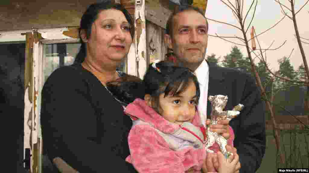 Mujic, Alimanovic, and their daughter pose in front of their house.