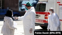 Medicinski radnik mjeri temperaturu jednoj ženi prije nego joj se dozvoli pristup bolnici, Sarajevo, 9. april