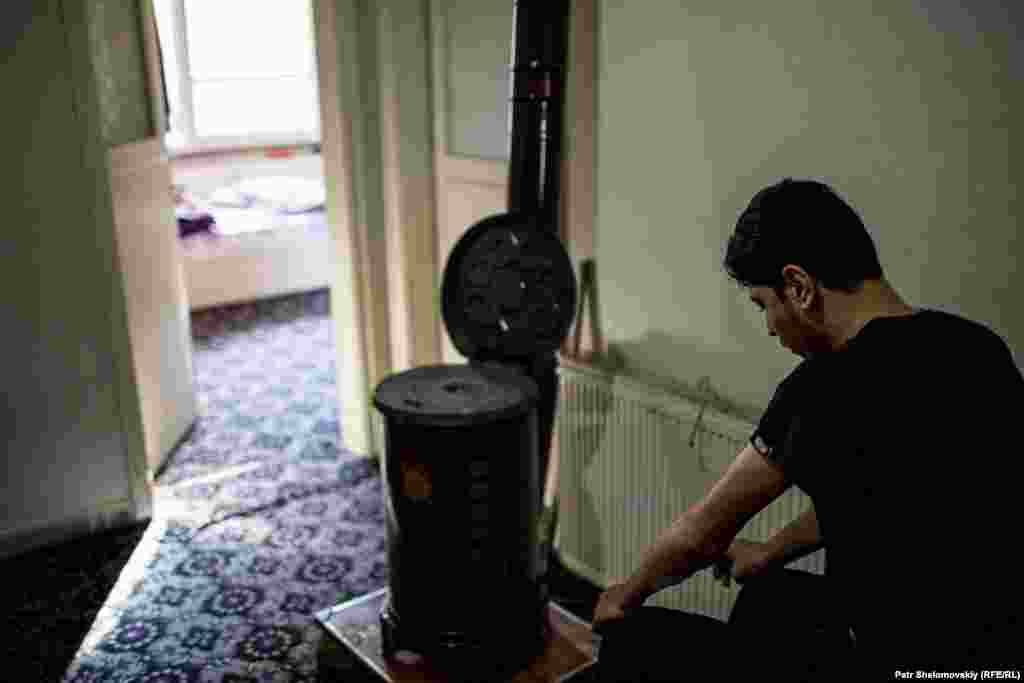 A wounded fighter prays while sitting on a plastic chair. His leg injury prevents him from kneeling.&nbsp;