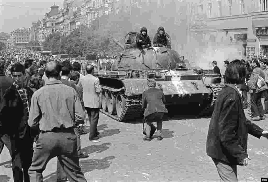 A photographer approaches a Soviet tank to take a photo on central Wenceslas Square.