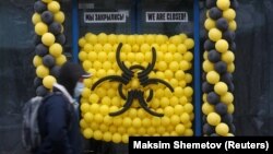 A pedestrian wearing a protective mask walks past a warning sign made of balloons outside a closed cafe in Moscow on March 30.