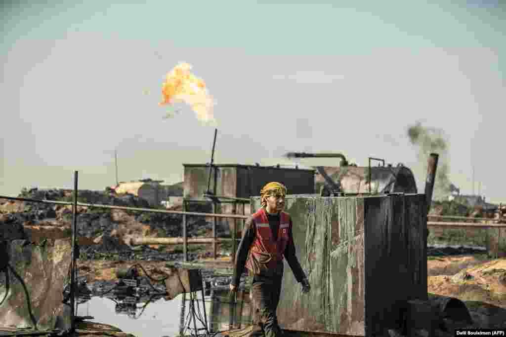 A Syrian worker walks at a primitive oil refinery in the countryside in Syria&#39;s northeastern Hasakeh Province near the Turkish border. (AFP/Delil Souleiman)