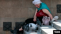 Женщина кормит голубей на лестнице, ведущей в метро. Москва, 27 июня 2013 года.