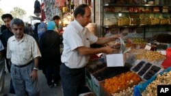 A shopkeeper works at his shop, as people pass, at the Tehran's old main Bazaar, Iran, Monday, Sept. 1, 2008