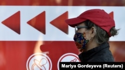 A woman wearing a face mask stands in line outside a pharmacy in Almaty, Kazakhstan.