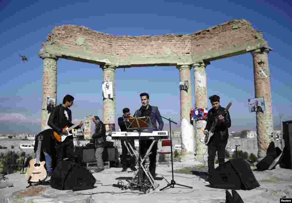 An Afghan band performs at the ruins of the Darul Aman palace in Kabul during a campaign called One Thousand Smiles For Peace by the Non-Violent World Organization (NVWO). A military helicopter flies on the left. (Reuters/Ahmad Masood)