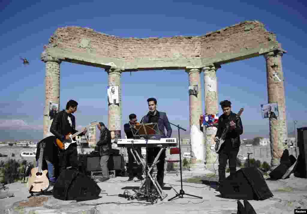 Një bend afgan performon në rrënojat e pallatit Darul Aman në Kabul, gjatë një fushate të quajtur &quot;Njëmijë buzëqeshje për paqe&quot;, nga Organizata Botërore pa Dhunë (NCWO). Ndërkohë, një helikopter ushtarak fluturon në të majtë.&nbsp;