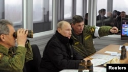 Президент России Владимир Путин (в центре) наблюдает за ходом военных учений. Ленинградская область, 3 марта 2014 года.