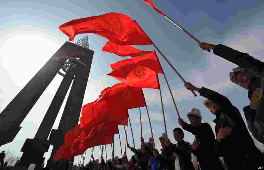 Kyrgyz men wearing traditional hats hold national flags during a rally marking National Flag Day in Bishkek on March 3. (AFP/Vyacheslav Oseledko)