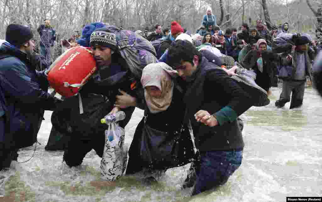 Migrants wade across a river near the Greek-Macedonian border, west of the village of Idomeni, Greece. (Reuters/Stoyan Nenov)