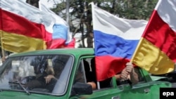 People wave Russian and South Ossetian flags in Tskhinvali, the South Ossetia capital, after Russia recognized the region as independent.