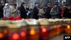 People wait for their turn to lay flowers and place candles at a memorial to the victims of Soviet-era political repression on Lubyanka Square in Moscow.