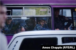 Police look on from their bus as their colleagues attempt to clear the top of Yerevan's Mashtots avenue of parked cars and protesters on April 25.