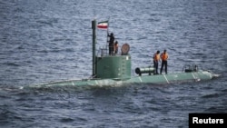 Iranian military personnel place a flag on a submarine during the Velayat-90 war games in the Strait of Hormuz on December 27.