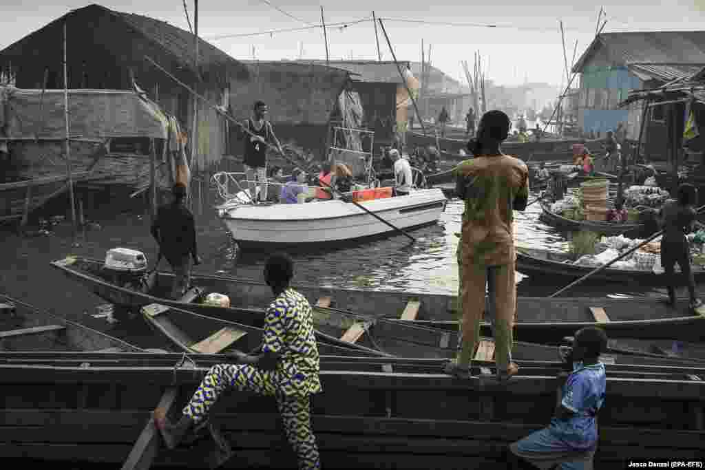 A boat with tourists from Lagos Marina is steered through the canals of the Makoko community -- an ancient fishing village that has grown into an enormous informal settlement on the shores of Lagos Lagoon in Nigeria. Contemporary Issues -- First Prize, Singles (Jesco Denzel) 