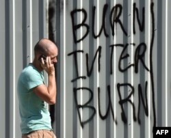 Un demonstrant tree pe lângă un graffiti cu "Burn Inter, burn", in Kiev, 5 sept., 2016
