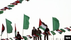 Young Hamas supporters are surrounded by Hamas and Palestinian flags as they put the last touches on preparations for today's celebrations.