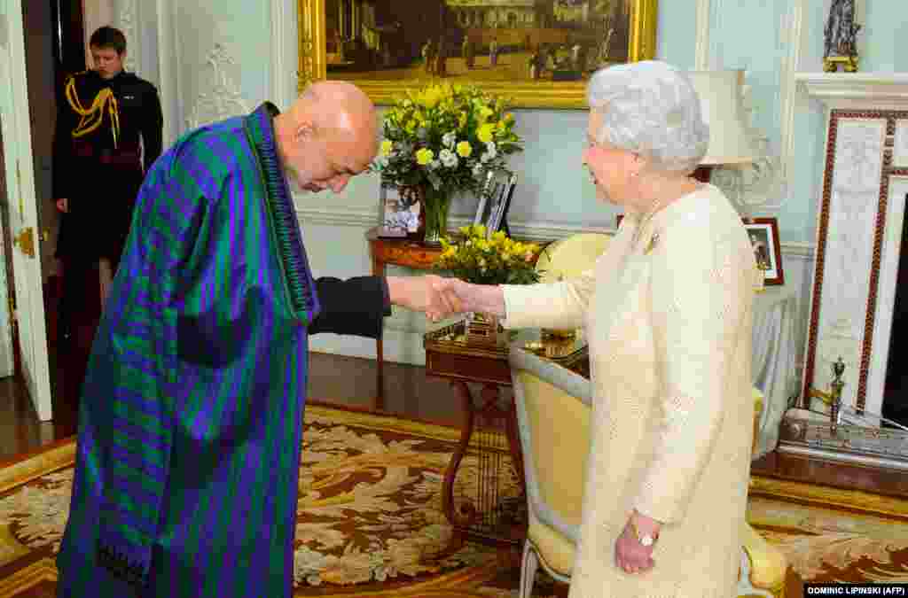 Britain's Queen Elizabeth II (right) shakes hands with Afghan President Hamid Karzai upon his arrival for an audience at Buckingham Palace in central London on October 30. (AFP/Dominic Lipinski)