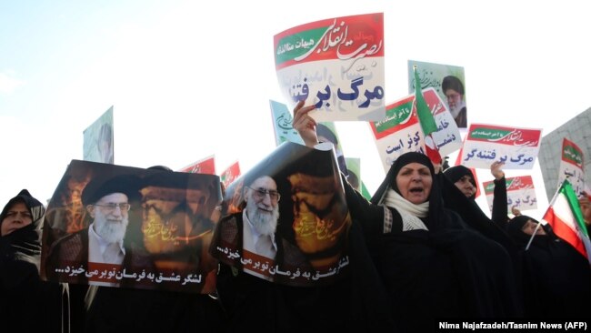 Iranian pro-government supporters hold posters of Supreme Leader Ayatollah Ali Khamenei during a rally in support of the regime in the city of Mashhad on January 4.