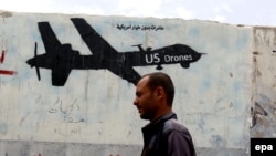 A Yemeni man walks past a graffiti showing a U.S. drone in Sanaa.