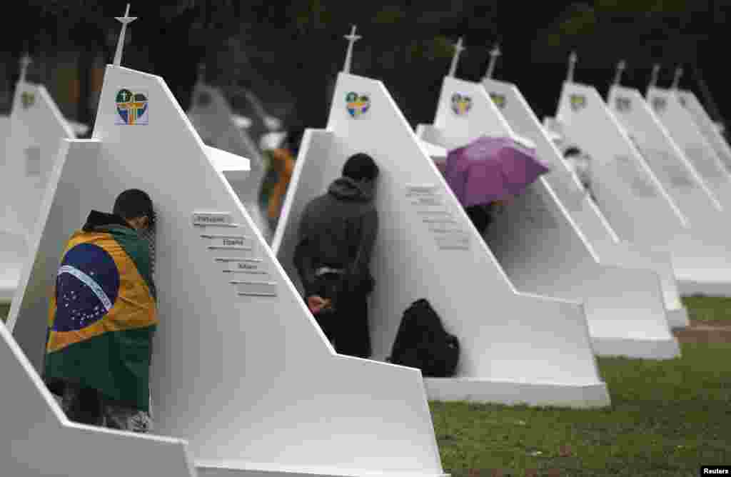 People confess at confessional booths set up at Quinta da Boa Vista Park as part of World Youth Day in Rio de Janeiro. Pope Francis urged young people to shun the "ephemeral idols" of money and pleasure and cherish traditional values to help build a better world. (Reuteres/Sergio Moraes)