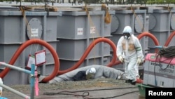 A worker walks in front of water tanks at Tokyo Electric Power Company's (Tepco) tsunami-crippled Fukushima Daiichi nuclear power plant in Fukushima prefecture on June 12.