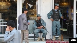 Afghan security personnel secure the front of a damaged building a day after insurgents used it to attack the parliament building in Kabul on April 15.