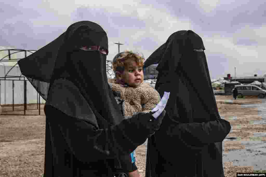 A woman walks carrying a toddler at the Kurdish-run Al-Hol camp for the displaced, where families of Islamic State fighters are held, in northeastern Syria. (AFP/Delil Souleiman)