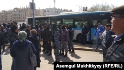 Участники митинга в Нур-Султане напротив сотрудников спецназа и пригнанных автобусов, в которые усадили задержанных. Нур-Султан, 1 мая 2019 года.