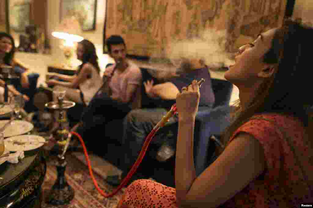 Sarah (right) and her brother, artist Usman Ahmed (second from right), smoke a water pipe, also known as a narghile, as they sit with friends at home in Islamabad.