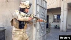 An Iraqi security forces member takes his position with his weapon during clashes with Al-Qaeda-linked militants in the city of Ramadi on February 11.