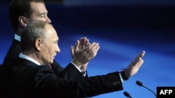 Dmitry Medvedev (back) and Vladimir Putin wave to delegates at a United Russia congress in Moscow on November 27.