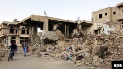 Жители рядом с разрушенными в результате авианалета зданиями в пригороде Саны. Ноябрь 2016 года.