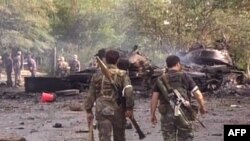 A Russian TV grab shows South Ossetian separatists walking near a burning Georgian tank in Tskhinvali.