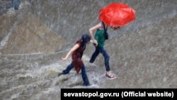 Люди, идущие под проливным дождем. Иллюстративное фото.