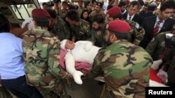 Army soldiers assist a diplomat who was injured in a helicopter crash in northern Pakistan, after he arrived with others at Nur Khan air base in Islamabad on May 9.