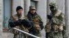 Pro-Russian gunmen stand guard outside the mayor's office in Slovyansk, Ukraine, on April 14. Can Kyiv prove some are Russian servicemen?