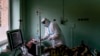 Український лікар у захисному костюмі від коронавірусу допомагає пацієнту з кисневою маскою в реанімаційному відділенні обласної лікарні в Україні (архівне фото)