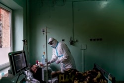 Лікар Костянтин Дроник, одягнений у спеціальний костюм для захисту від коронавірусу, допомагає пацієнтові з кисневою маскою у відділенні інтенсивної терапії в обласній лікарні в Чернівцях, 4 травня 2020 року