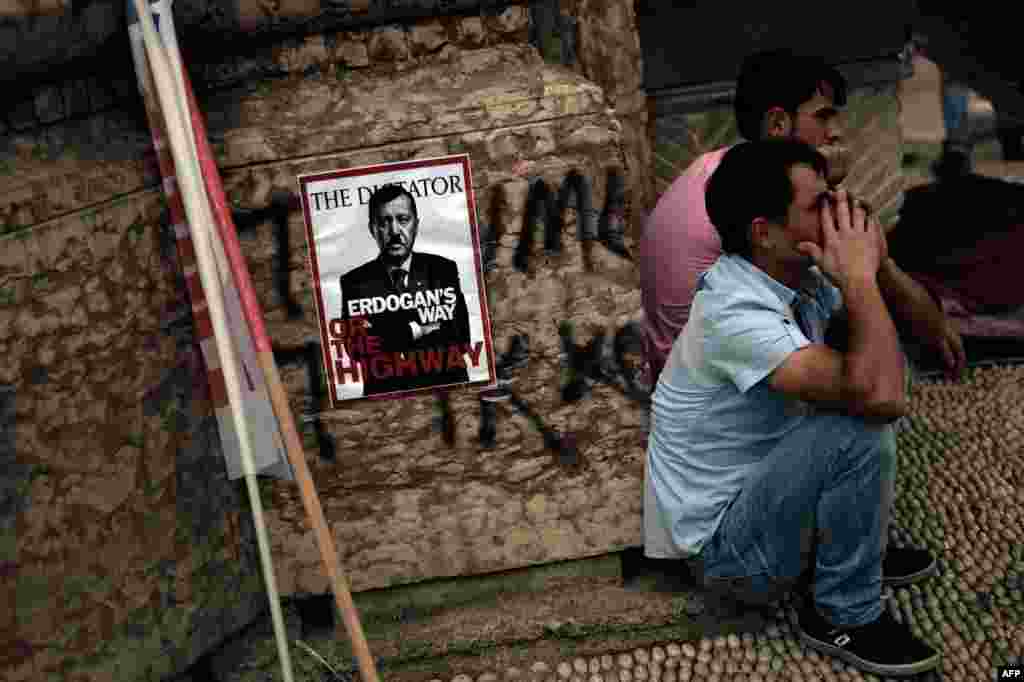 People sit near a poster portraying Prime Minister Recep Tayyip Erdogan as Nazi leader Adolf Hitler in Istanbul on June 5.