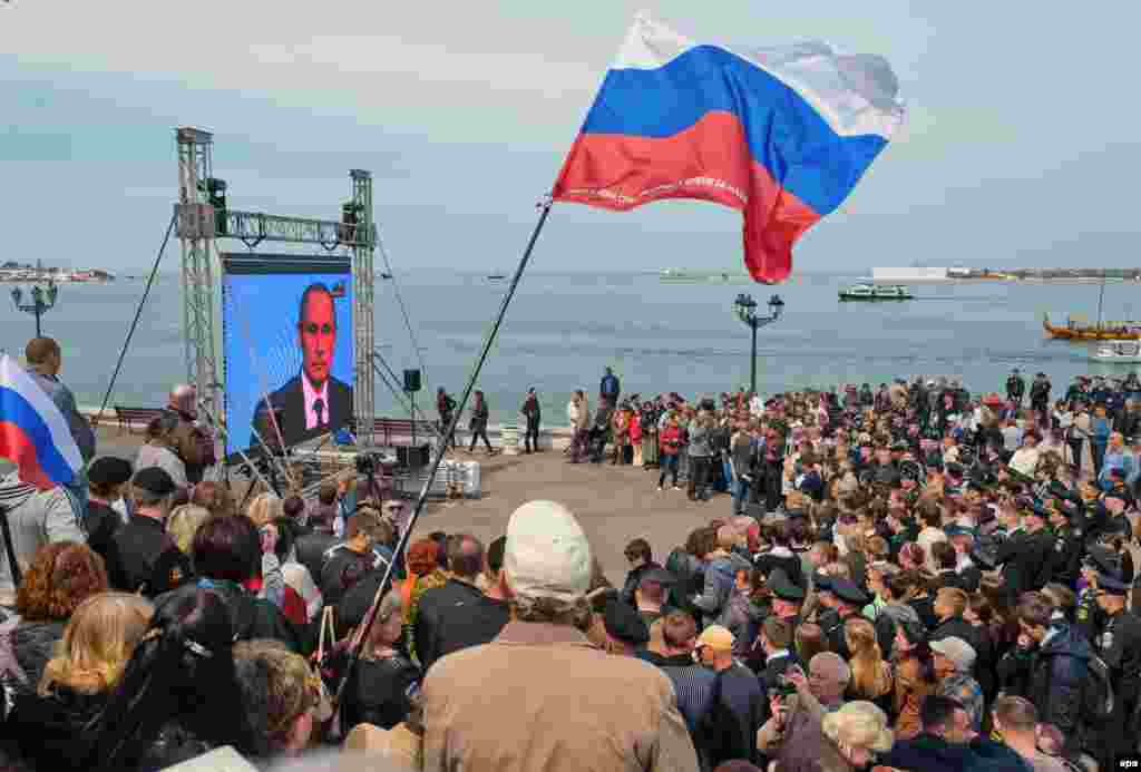 Crimean people watch a TV broadcast with Russian President Vladimir Putin speaking during his annual call-in live broadcast, on the seafront in Sevastopol, Crimea, on April 17. (epa/Anton Pedko)